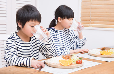 Obraz na płótnie Canvas 食事中に水を飲む子供