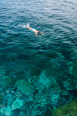 a man dives with glasses and tube and bathes in the sea with turquoise blue color