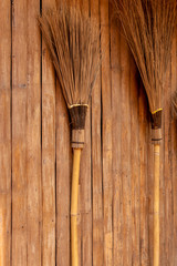 The broom is leaning against a wooden wall.