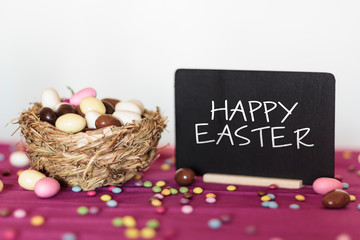 Nest with easter almonds and blackboard with Happy Easter text