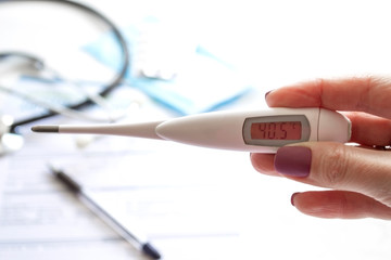 The doctor holds a thermometer with a high temperature. Temperature measurement