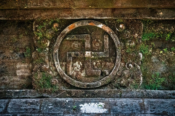 A symbol of divinity and spirituality in Hinduism and Buddhism, the ancient swastika is carved into stone on the wall of a temple in Bali, Indonesia.