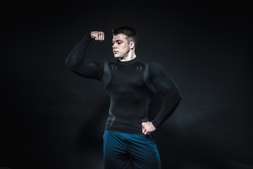 Sexy young athlete posing on a black background in the Studio. Fitness, bodybuilding