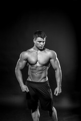 Sexy young athlete posing on a black background in the Studio. Fitness, bodybuilding, black and white