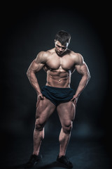 Sexy young athlete posing on a black background in the Studio. Fitness, bodybuilding