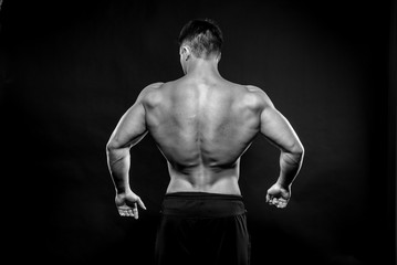 Sexy young athlete posing on a black background in the Studio. Fitness, bodybuilding, black and white