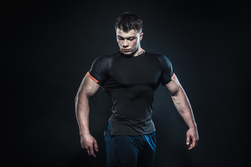 Naklejka premium Sexy young athlete posing on a black background in the Studio. Fitness, bodybuilding