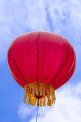 Guilin, China - May 10, 2010: Small red hot air balloon with golden trim floats under blue...