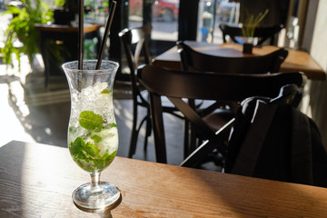 Mojito in a glass with a tube on the cafe table