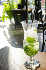 Mojito in a glass with a straw on a cafe table