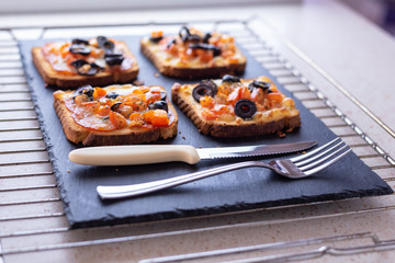 Young female chef in kitchen at home preparing mozzarella salami tomato and olives sandwiches. Healthy eating