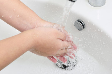 Washing hands with soap under under running water.   