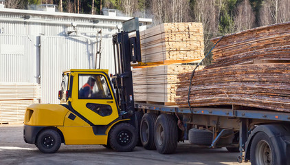 The machine loads the boards, lumber from the finished goods warehouse onto the truck