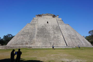 Fototapeta na wymiar Uxmal, Mexico: Tourists visit the Mayan Pyramid of the Magician, also known as The Pyramid of the Dwarf, 600-900 A.D.