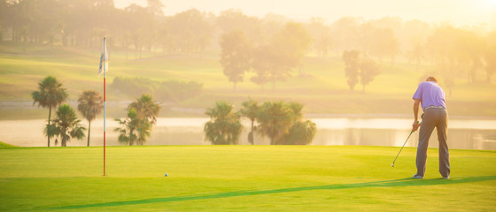 Golfers putting golf balls on the green amid the warm sunshine in the morning. Concept of Outdoor activities and Outdoor sports, Concept of Golfer and Lifestyle. - obrazy, fototapety, plakaty