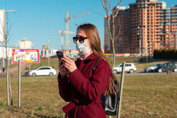 girl on the street with a mobile phone in her hands. face mask to protect against viruses....