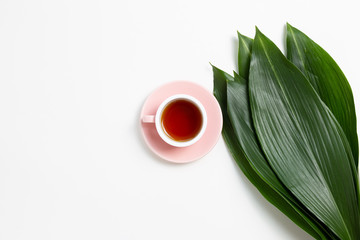 Cup of black tea with fresh green leaves on white background. Flat lay, top view, copy space