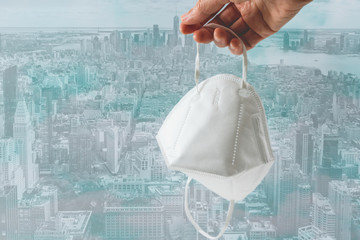 Protection mask KN-95 in hand  with New York City skyline background. Prevention of the spread of virus and epidemic, social issues, diseases, flu, air pollution, corona virus concept