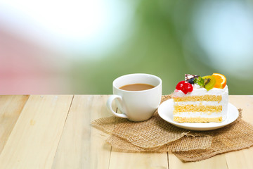 Slice cake with coffee cup on wood , green blur background