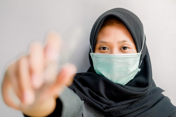 The concept of coronavirus and air pollution. portrait of young Asian girl wearing a mask to protect covid-19 and showing hand gestures to use a hand sanitizer. Coronavirus virus and epidemic virus