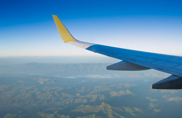 Fototapeta na wymiar Wing of an airplane on blue sky