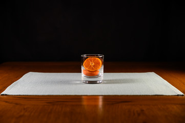 Isolated glass with sliced oranges inside on green mat ,black background