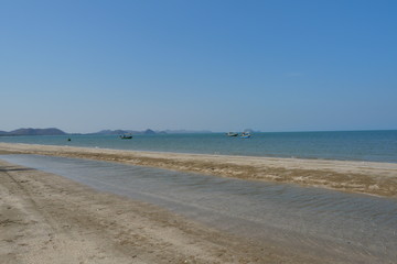 Sea wave splash the brown sand beach, Fishing boat float in the sea with island with mountain and blue sky in background, Khao Sam Roi Yot National Park , Prachuap Khiri Khan , Thailand