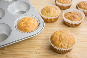 Little cupcakes freshly baked homemade muffins in a muffin pan and wooden board.