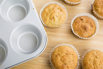 Little cupcakes freshly baked homemade muffins in a muffin pan and wooden board.