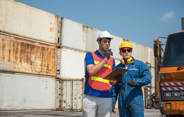 Foreman and dock worker staff working checking at Container cargo harbor holding clipboard. Business Logistics import export shipping concept.