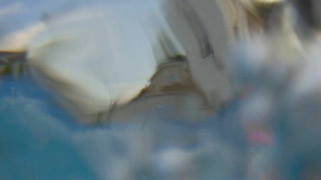 Wide Angle Hand Hold Shot Of Skinny Man Jumping From Top Of Ladder Into Back Yard Swimming Pool Creating Big Splash And More Waves.