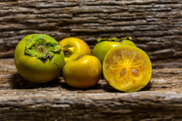 Persimmon fruits fresh and in halves on wooden construction background