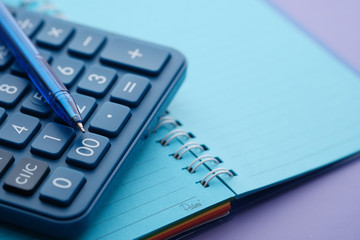 Close up of blue color pen, calculator and notepad