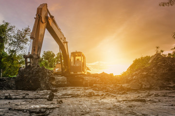 Backhoe with raised bucket at sunset