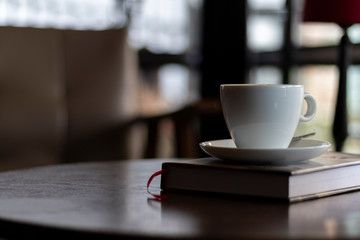 white cup of coffee capuccino over a book in a coffee shop