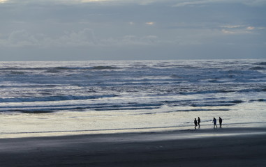 Fototapeta na wymiar Beachgoers newr Westport Jetty watching surf during sunset