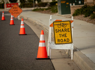 Share The Road sign with bicycle graphic and traffic cone