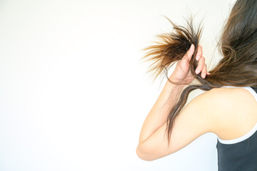 Cropped shot view of woman holding her damaged split ended hair. Hair care concepts, Hair damage is...