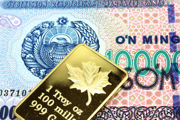 A macro image of a som note from Uzbekistan note with a Canadian one ounce gold ingot close up
