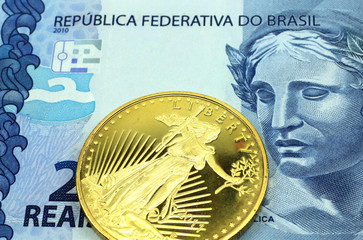 A macro image of a blue Brazilian two real bill with a gold coin.  Shot close up.