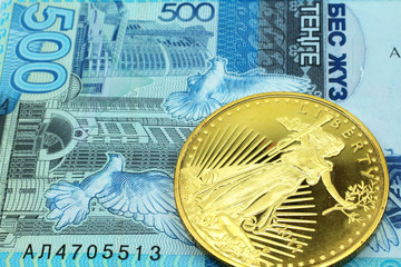 A macro image of a a blue 500 tenge note from Kazakhstan with a gold coin.  Shot close up.