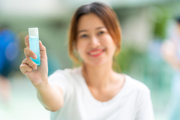 Asian Woman hand holding bottle of sanitizer alcohol gel or antibacterial soap for washing hands and fingers. Hygiene and protection spread of germs, bacteria and avoid infections coronavirus concept.