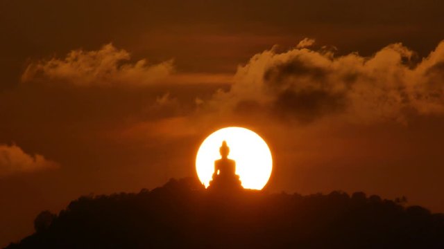 hue sunset over  silhouette Phuket big buddha statue on hilltop with many big trees high mountain in the beautiful evening colourful  orange twilight sky,moving cloud,  attraction tourist photo spot