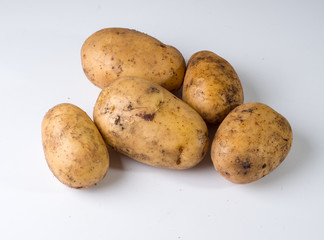 Several potatoes on a white surface. Studio photography