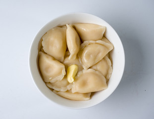 Freshly boiled dumplings in a white bowl. Top view