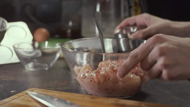 Spicing chicken meat on kitchen, shallow depth of field, slow motion