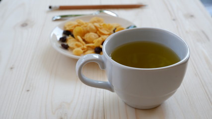 A cup of green tea and snack on wooden table