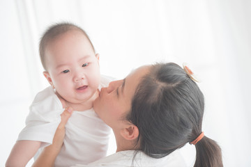 happy loving family. mother playing with her baby in the bedroom. asian mother hugging and holding her baby. family, motherhood, parenting, family and child care concept. White background.