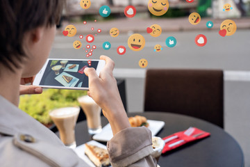 Female blogger influencer hold phone take food mobile photo on phone sit at cafe table. Girl...