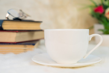 Cup of coffee with book stacked on table